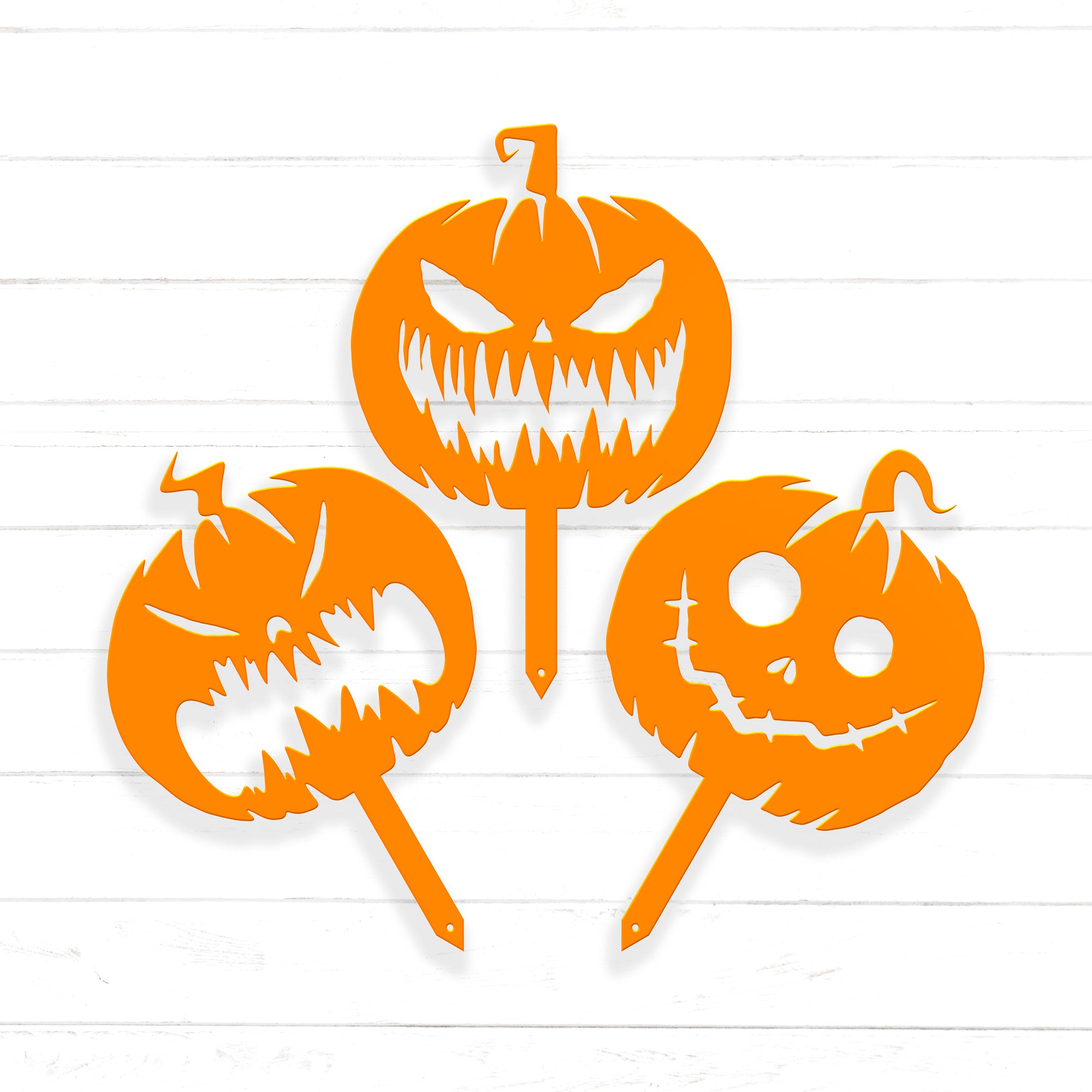 three orange Halloween-themed cutouts, including a jack-o-lantern with a menacing expression, a jack-o-lantern with a smiling face, and a jack-o-lantern with a menacing face.