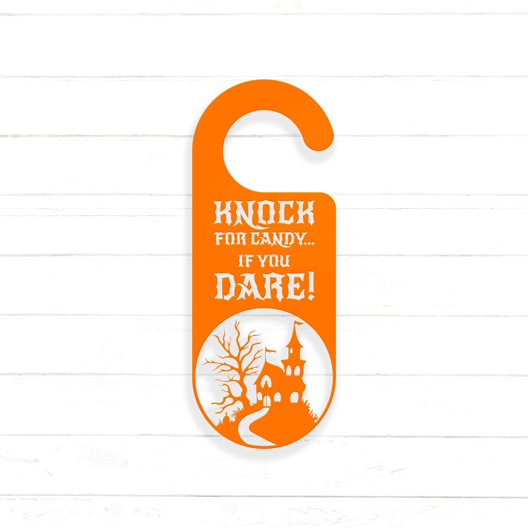 An orange door hanger with a castle silhouette and the text "KNOCK FOR CANDY... IF YOU DARE!" printed on it.
