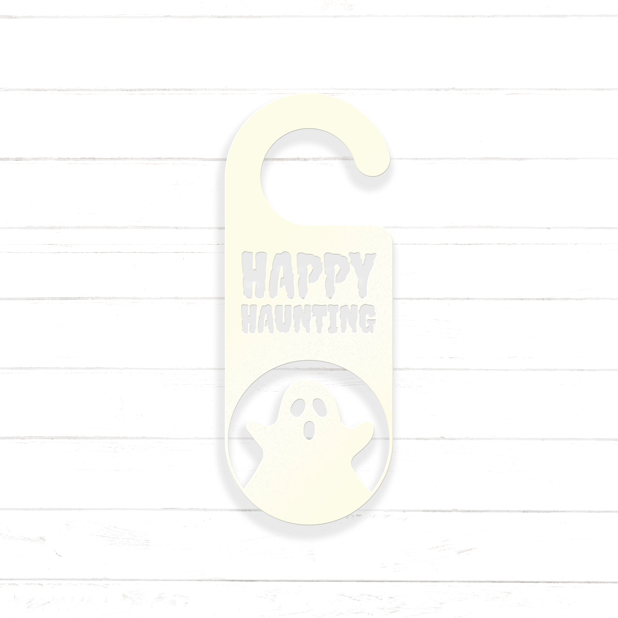 A white door hanger with the text "HAPPY HAUNTING" printed on it, along with a ghost silhouette.