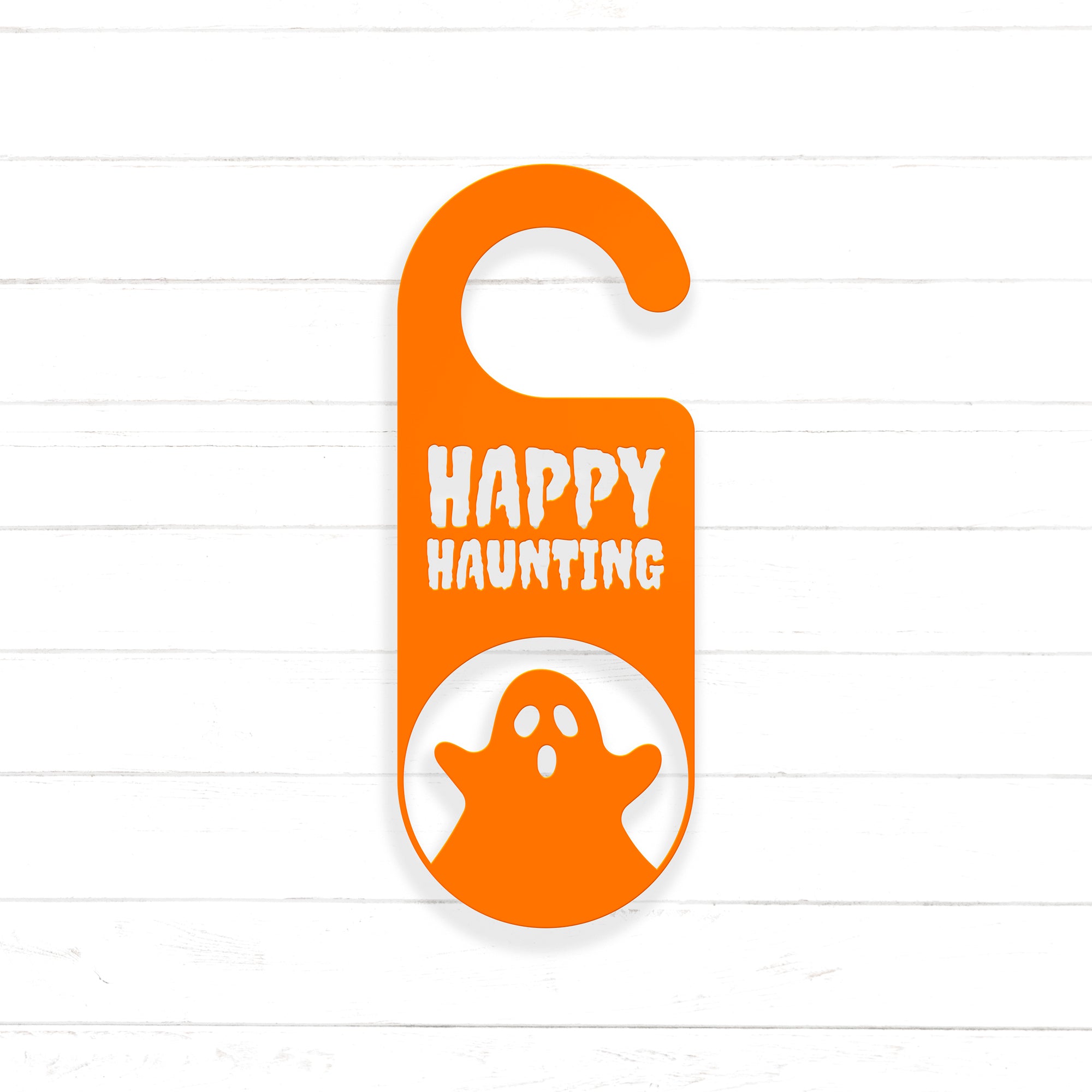 An orange door hanger with the text "HAPPY HAUNTING" printed on it, along with a ghost silhouette.