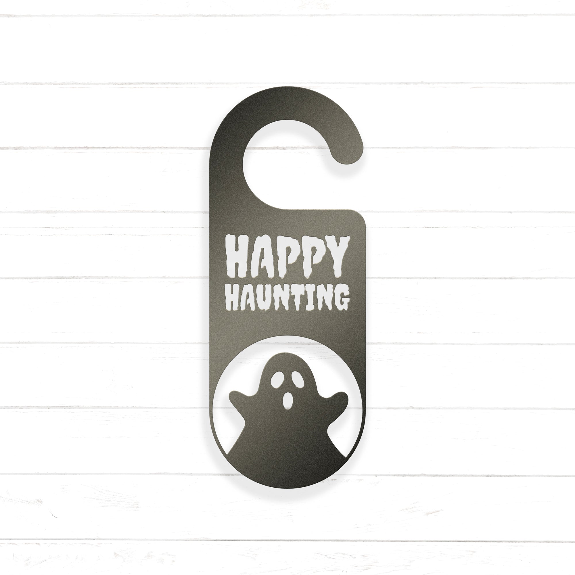 A black and white sign with the text "HAPPY HAUNTING" and a ghost silhouette, hanging on a wooden surface.
